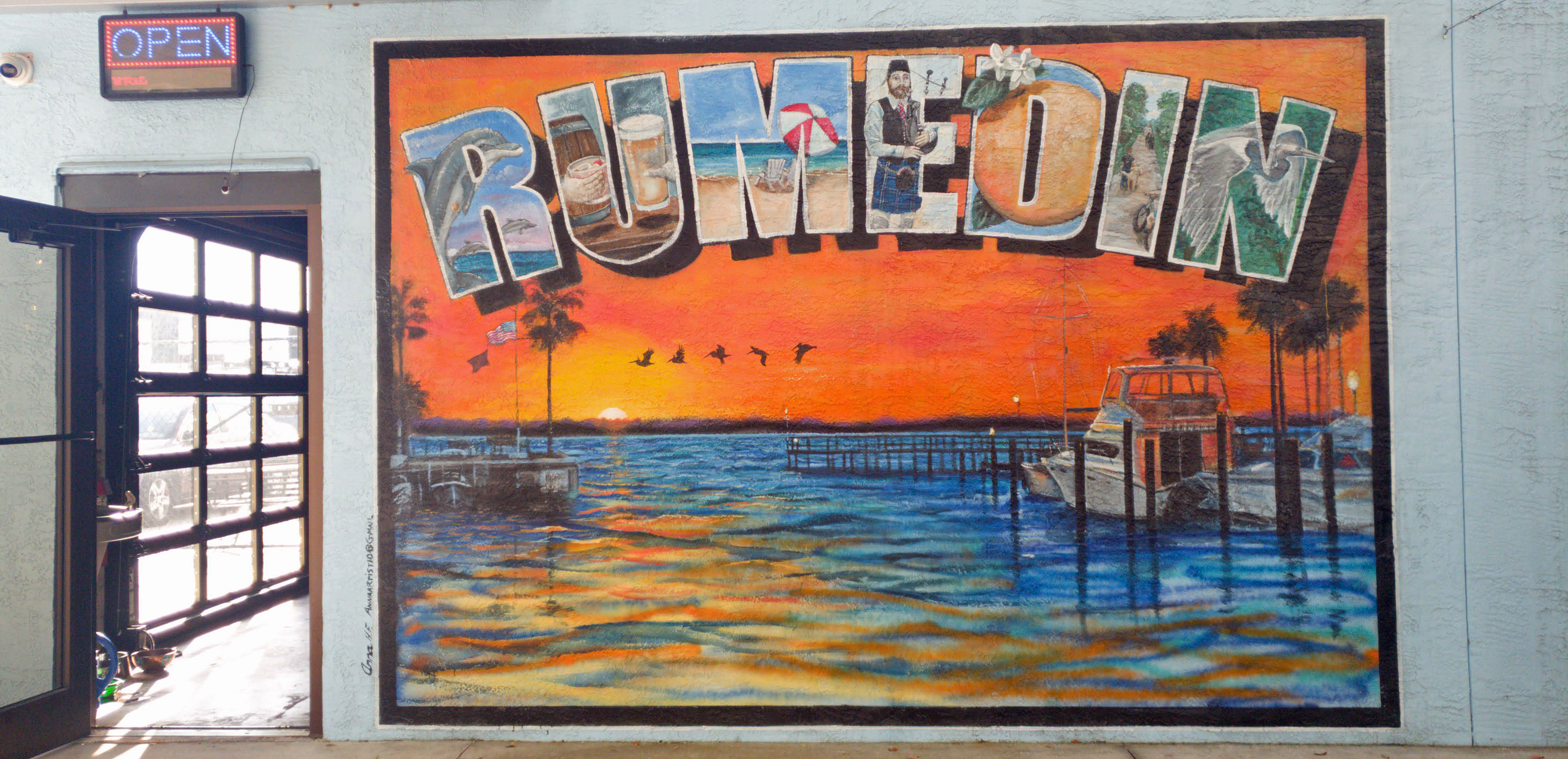 Beth Warmath mural at Cotherman Distilling Co in Dunedin Florida showing a sunset over Caladesi Island with pelicans and a fishing boat.