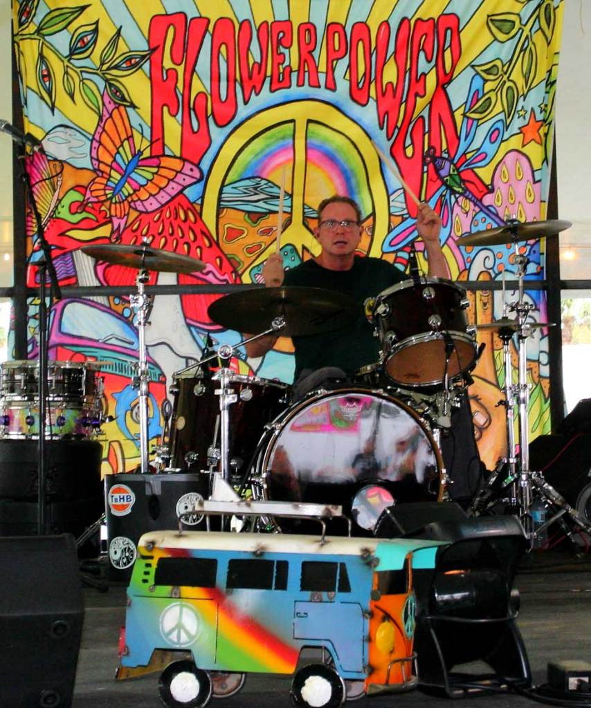 Drummer of St. Pete Sons performing live on the festival stage. In the center, the drummer plays his kit.