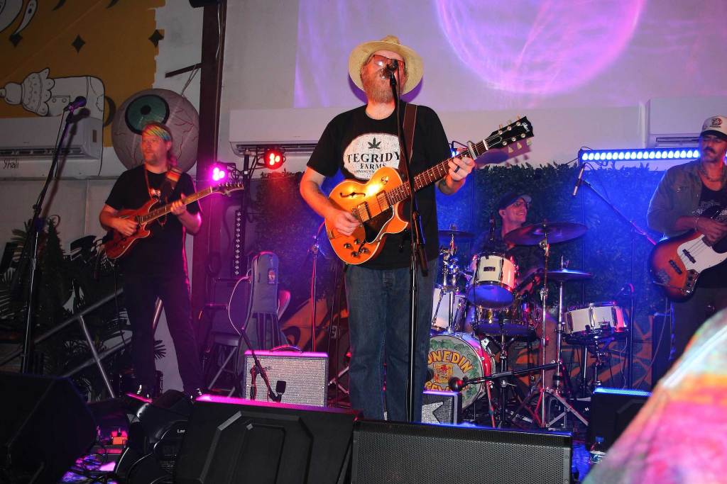 The Brock Butler Band performing live on stage with a frontman, two bass players, and a drummer.
