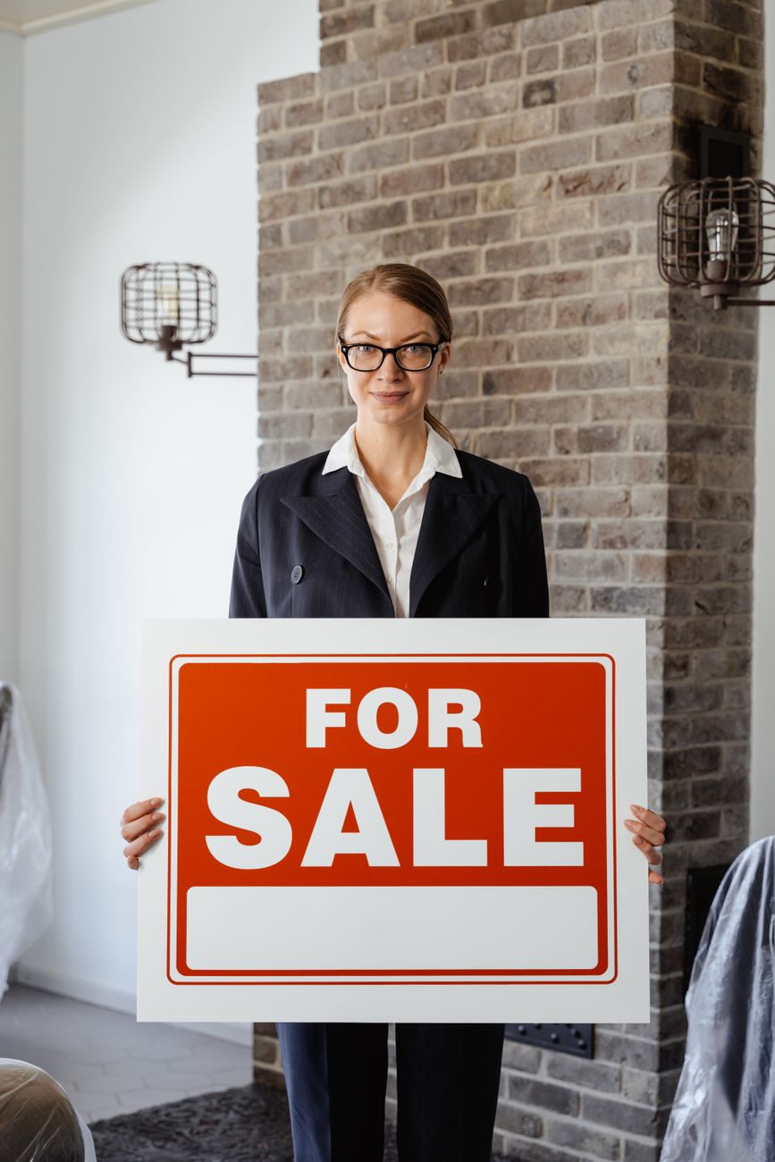 a real estate agent holding a sign